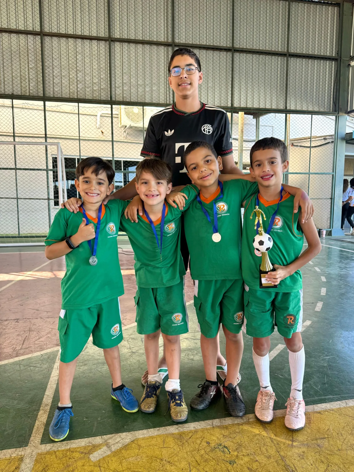 Alunos com medalhas e troféu de atividade esportiva